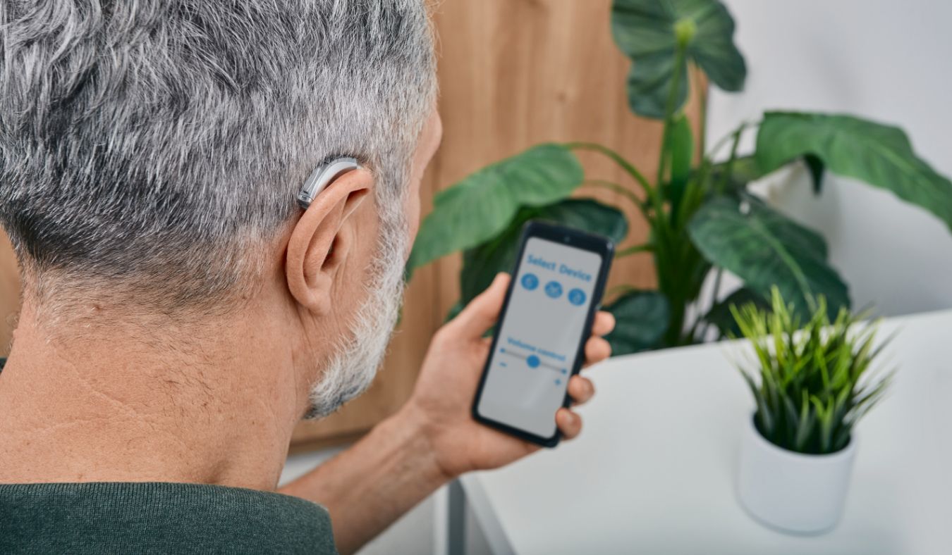hearing aid on ear mature man with phone app 1