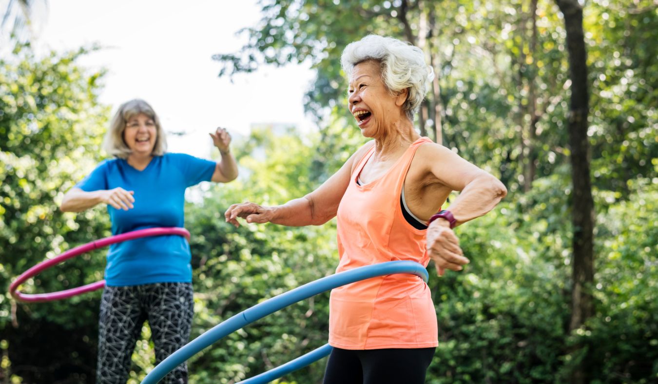 senior women exercising outside hula hooping