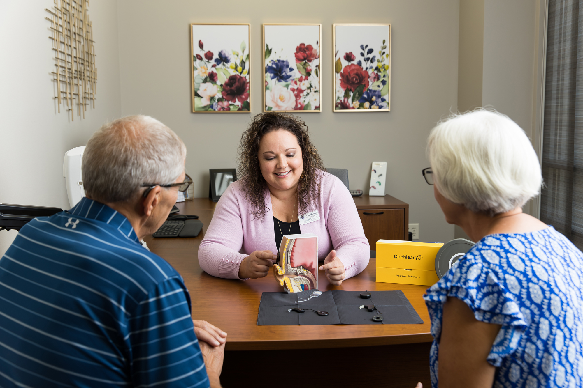 amanda demostrating to senior couple how cochlear implants work