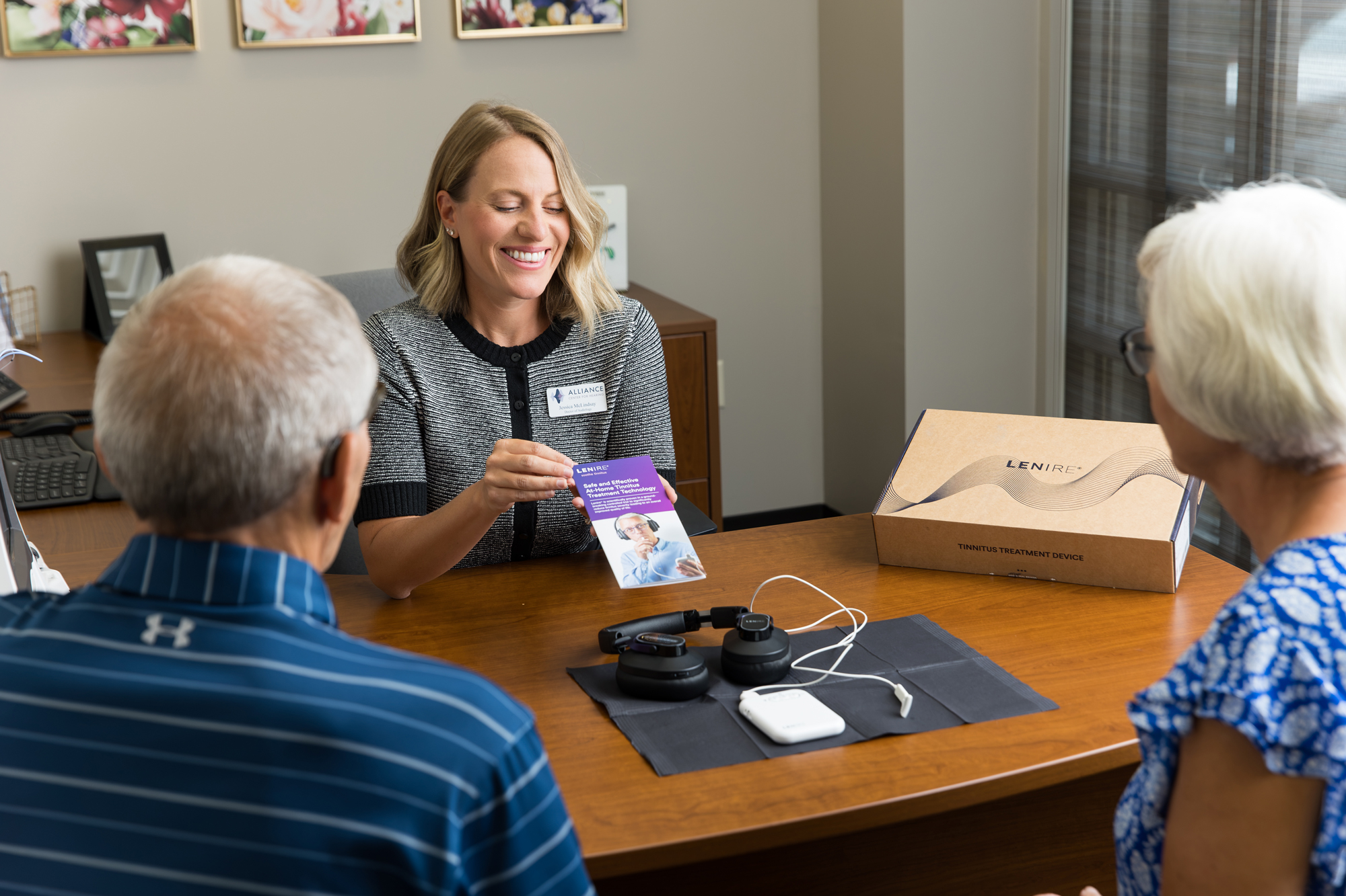 jessica showing senior couple patients a lenire tinnitus treatment brochure