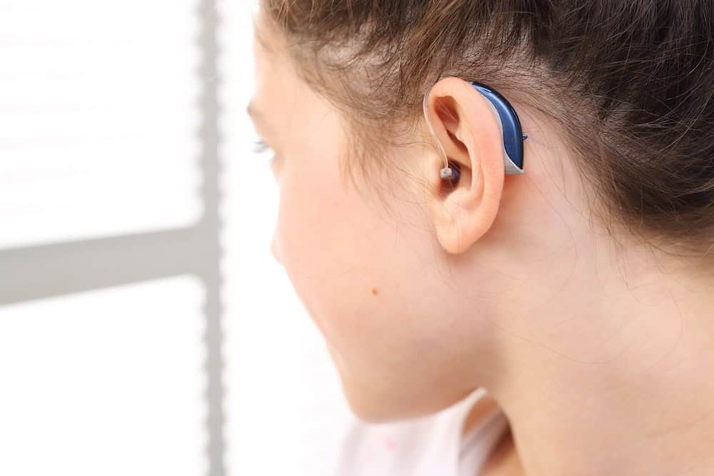 young woman showing off her new blue hearing aids