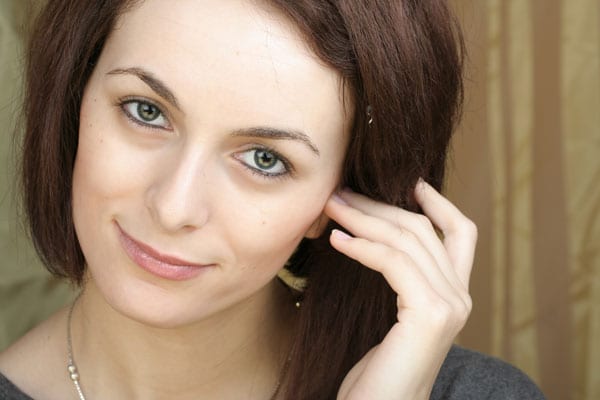 a brown haired woman touching her ear