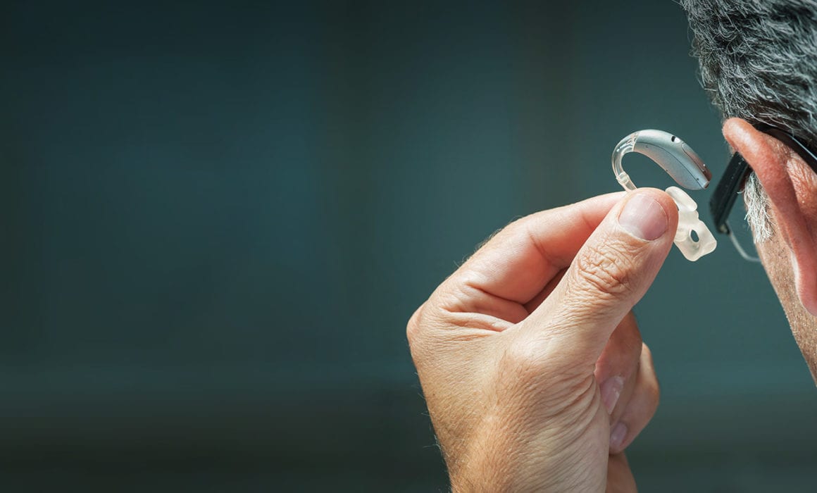 a man inserting a hearing aid into his ear