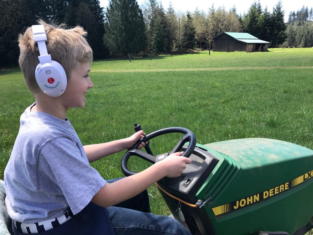 a kid mowing the lawn while using ear protection