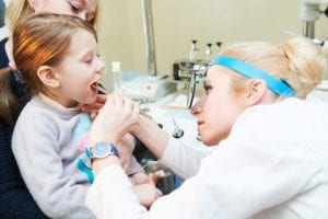 an ENT doctor checking a young child's mouth for infections