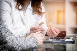 Doctor showing hearing aid to her patient in the doctor's office