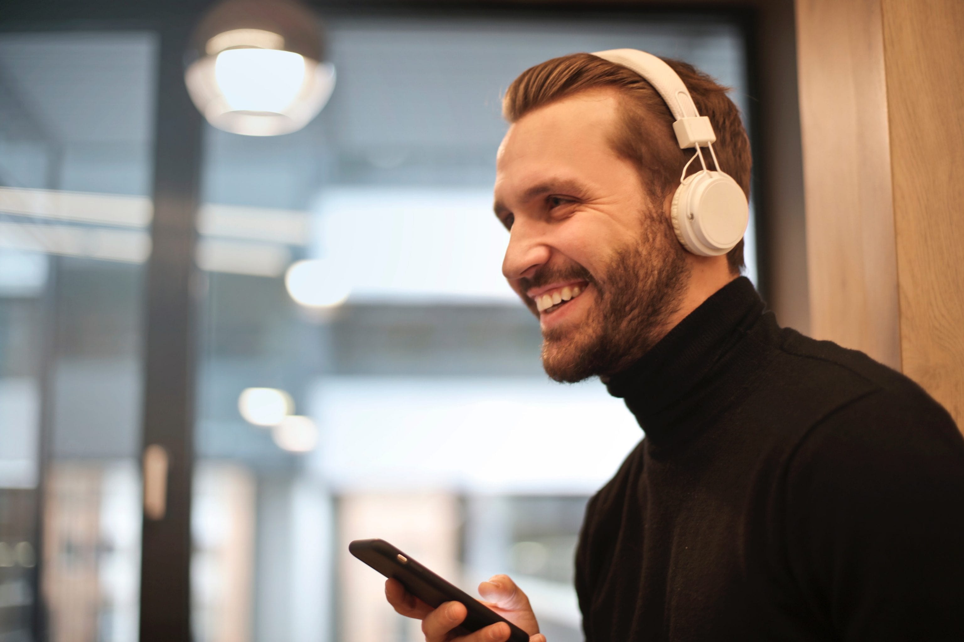 a man with facial hair is holding his phone and listening to music