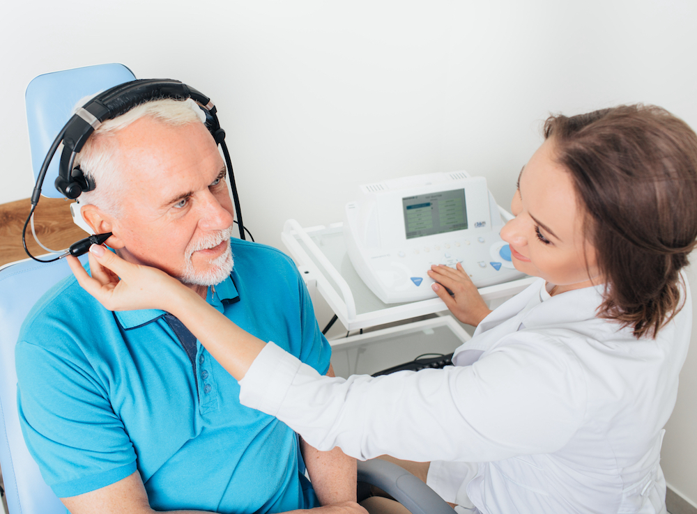 man in blue shirt seeing his audiologist for hearing aid evaluation