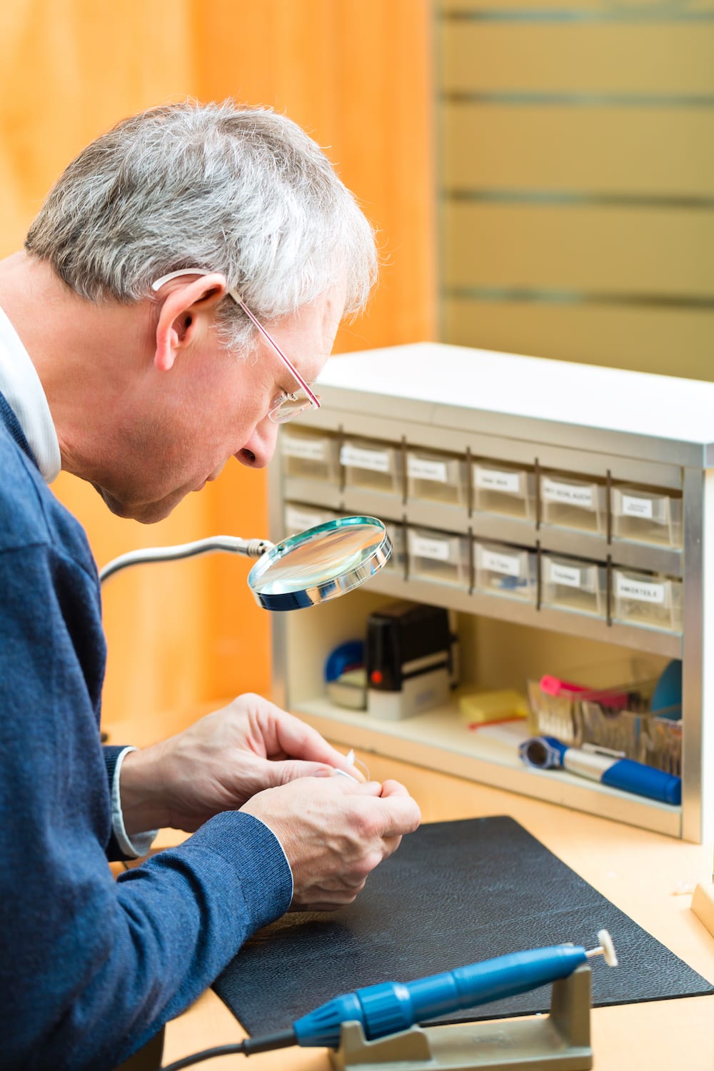a hearing specialist repairing a hearing device