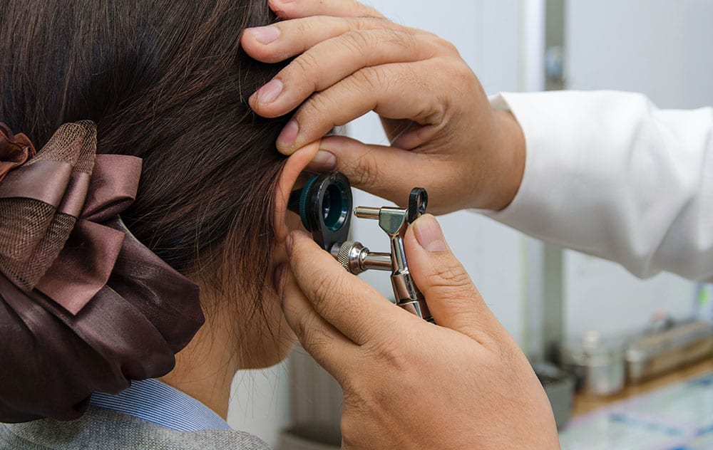 an audiologist is administering a professional ear exam