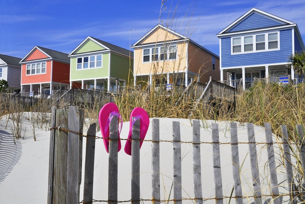four houses on beachfront with white sand and pink sandals