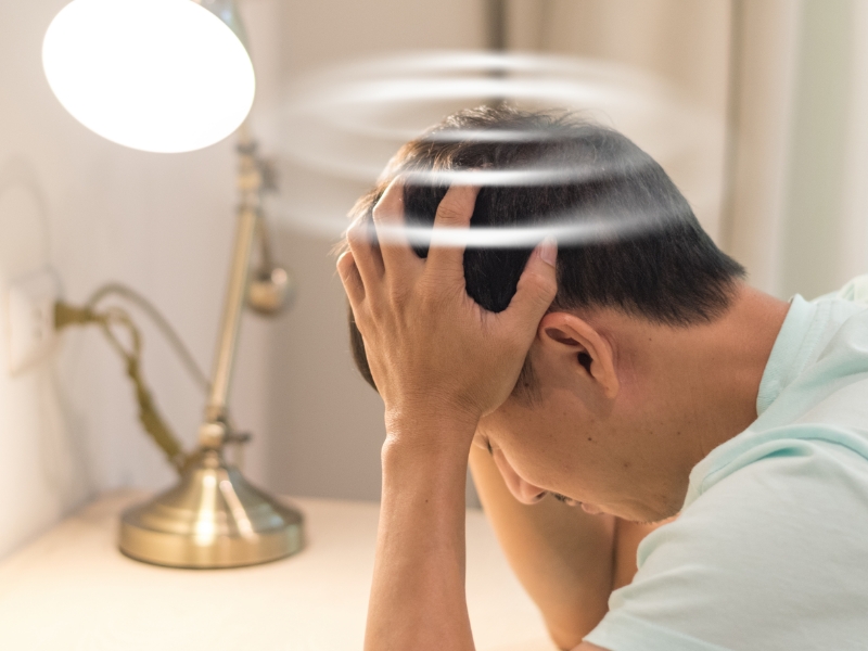 Adult man holds his head while showing visible discomfort.