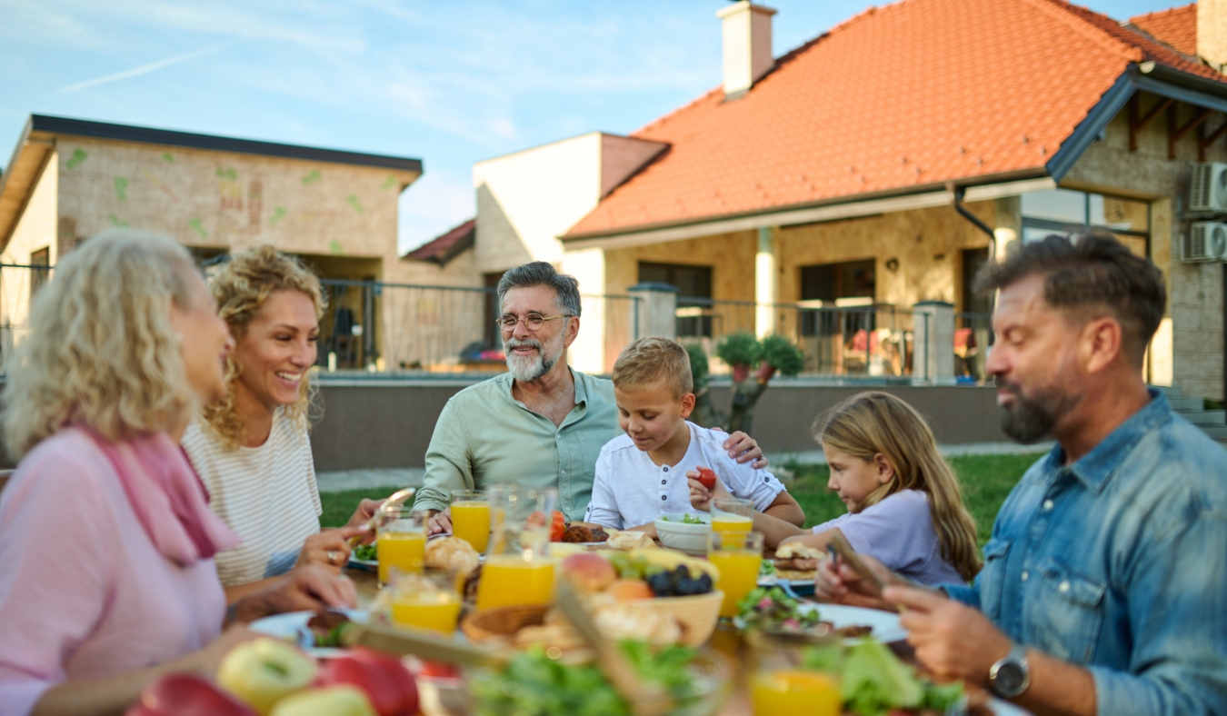 Multigenerational family is enjoying a meal together outdoors on a beautiful summer day