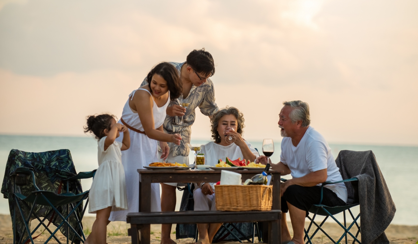 generation family little girl with parents and grandparents relax and enjoy with dinner party and dancing together on the beach