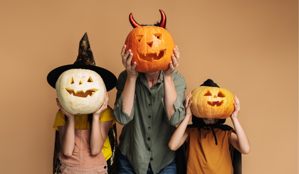 events halloween grandmother granddaughters holding jack o lanterns by face dressed up