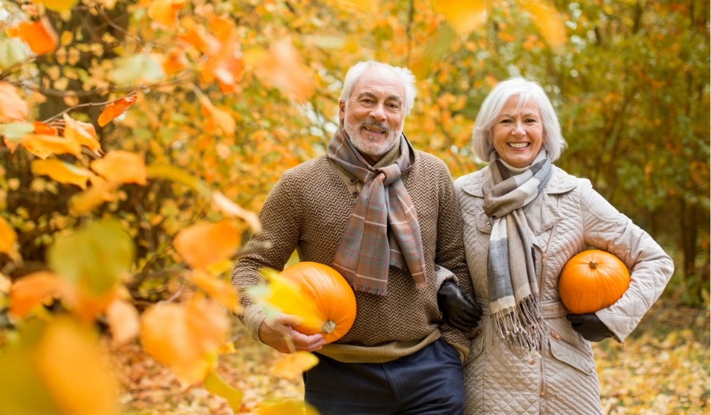 events halloween senior couple autumn foliage holding pumpkins