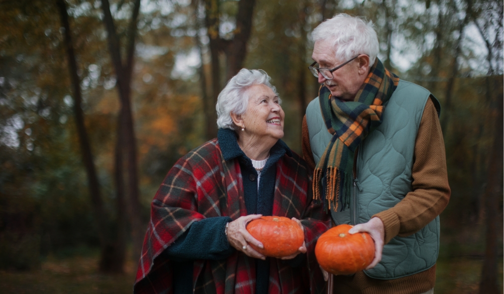 events halloween senior couple looking at each other while holding pumpkins