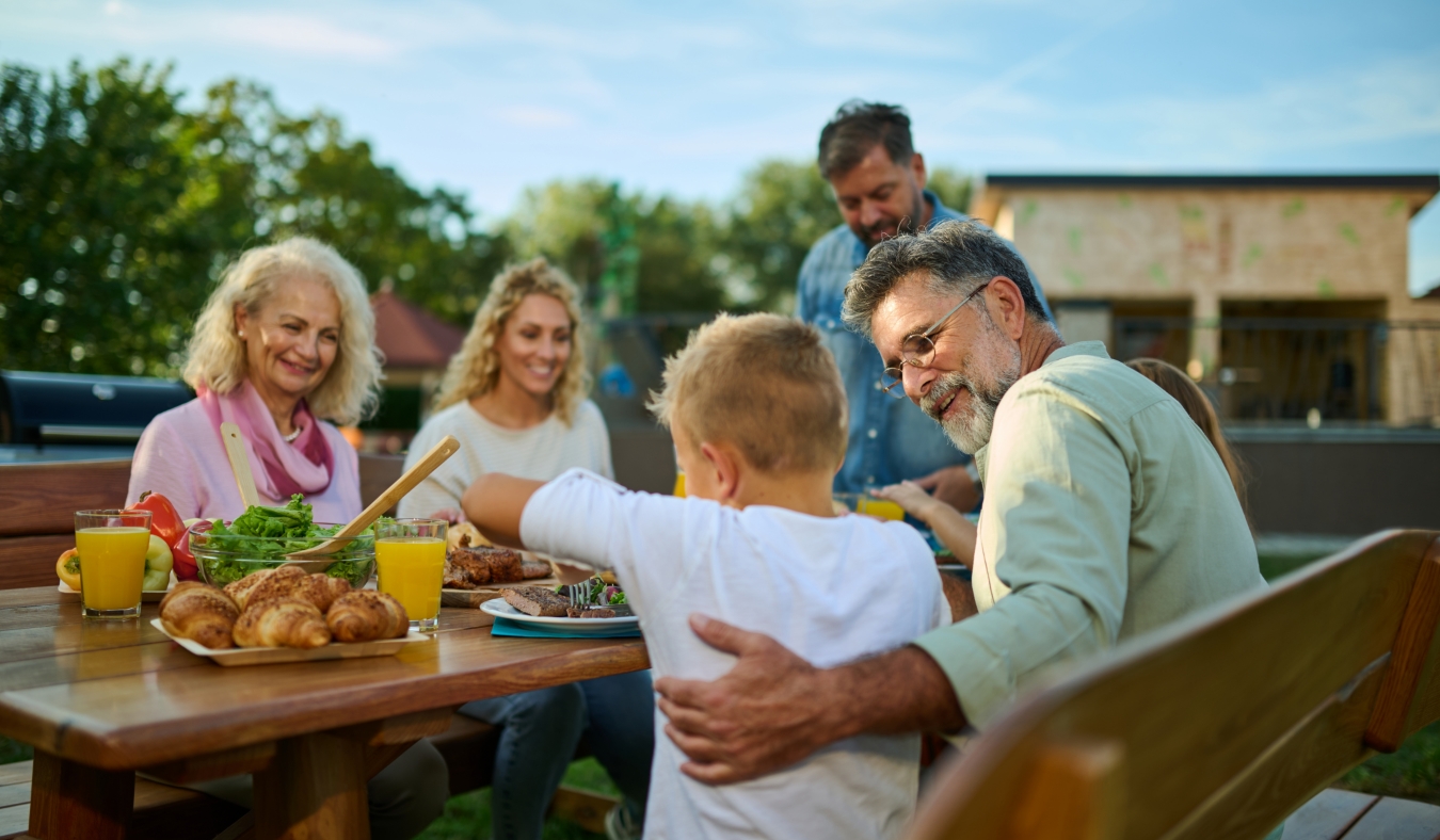 three generations of family enjoying meal late summer
