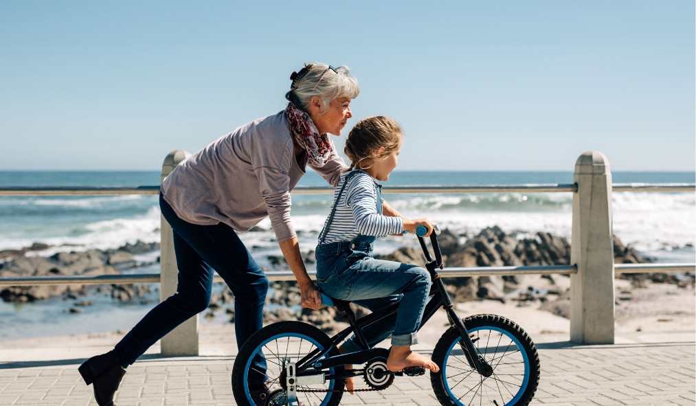 summer grandmother granddaughter ride bike by beachside