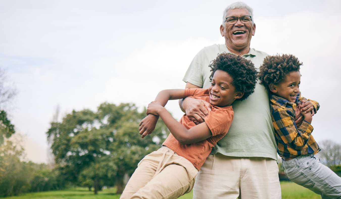 grandfather holding grandsons playing laughing outside