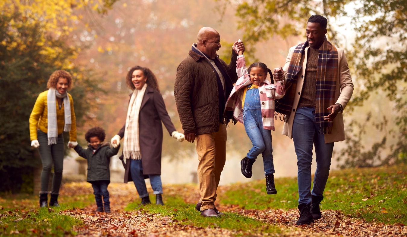 multi generation family playing in park during autumn weather