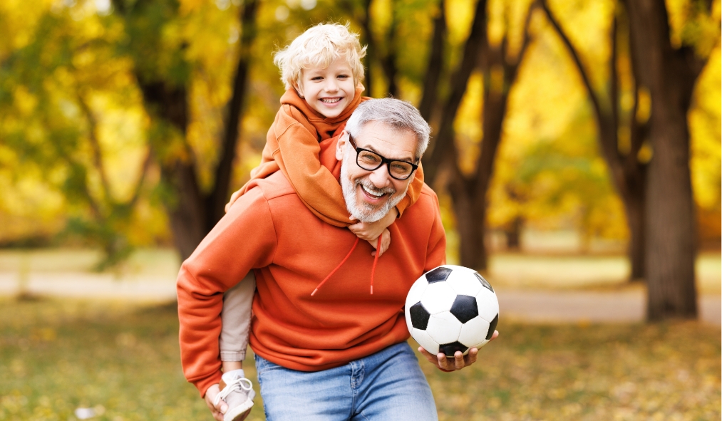 events autumn grandfather grandson piggy back ride playing soccer