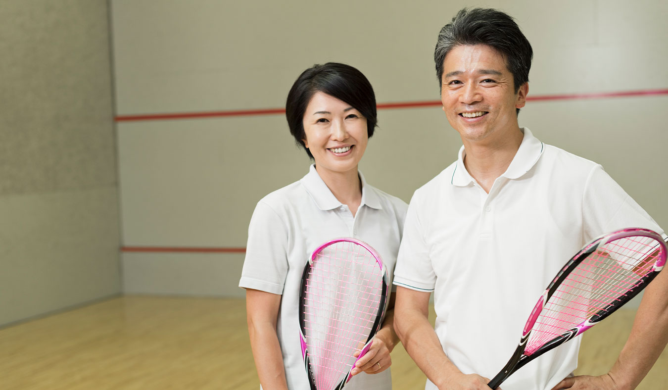 events senior asian couple smiling holding squash rackets