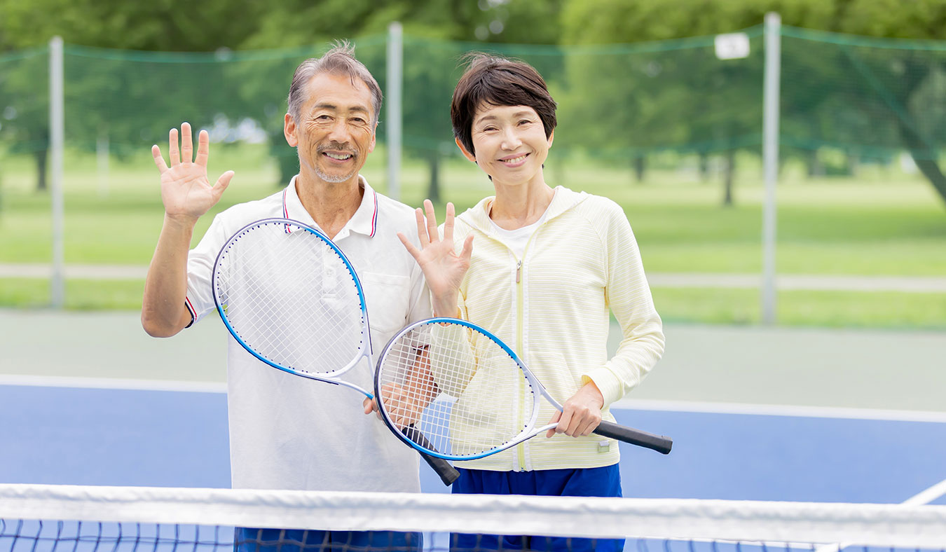 events senior asian couple smiling holding tennis rackets