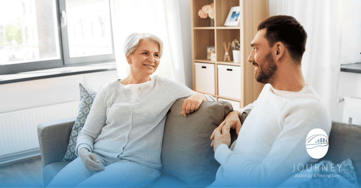 man and woman sitting on couch discussing hearing loss
