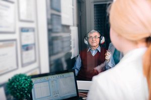 elderly patient sitting for hearing examination in audiologists office