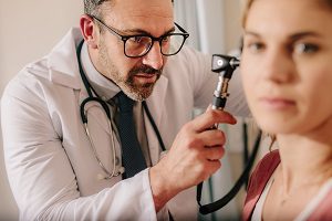 audiologist inspecting the ear canal of hearing loss patient