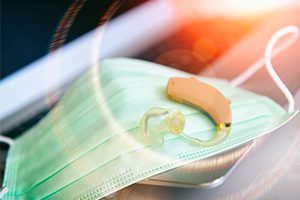 hearing aid resting upon green face mask