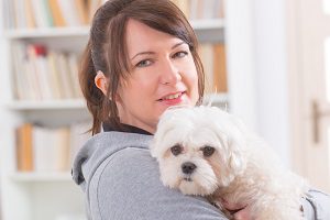 brunette woman holding her small dog in living room