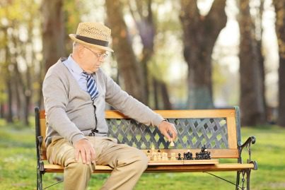 image of well dressed man playing chess outside on a bench