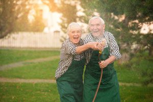 elderly husband and wife playing outside like children