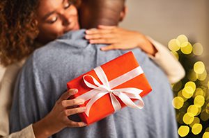 woman hugging husband with holiday gift in hand