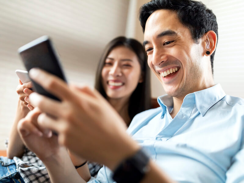 man and woman looking at phone and smiling