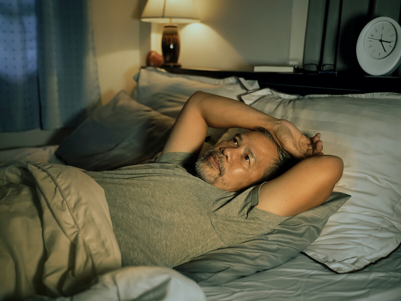 man struggling to sleep in his bed