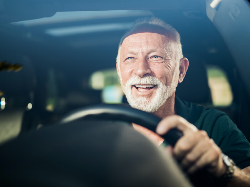 man smiling behind the wheel of a car