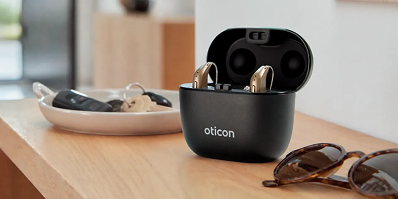 oticon reveal lifestyle portable charging case open on table with hearing aids