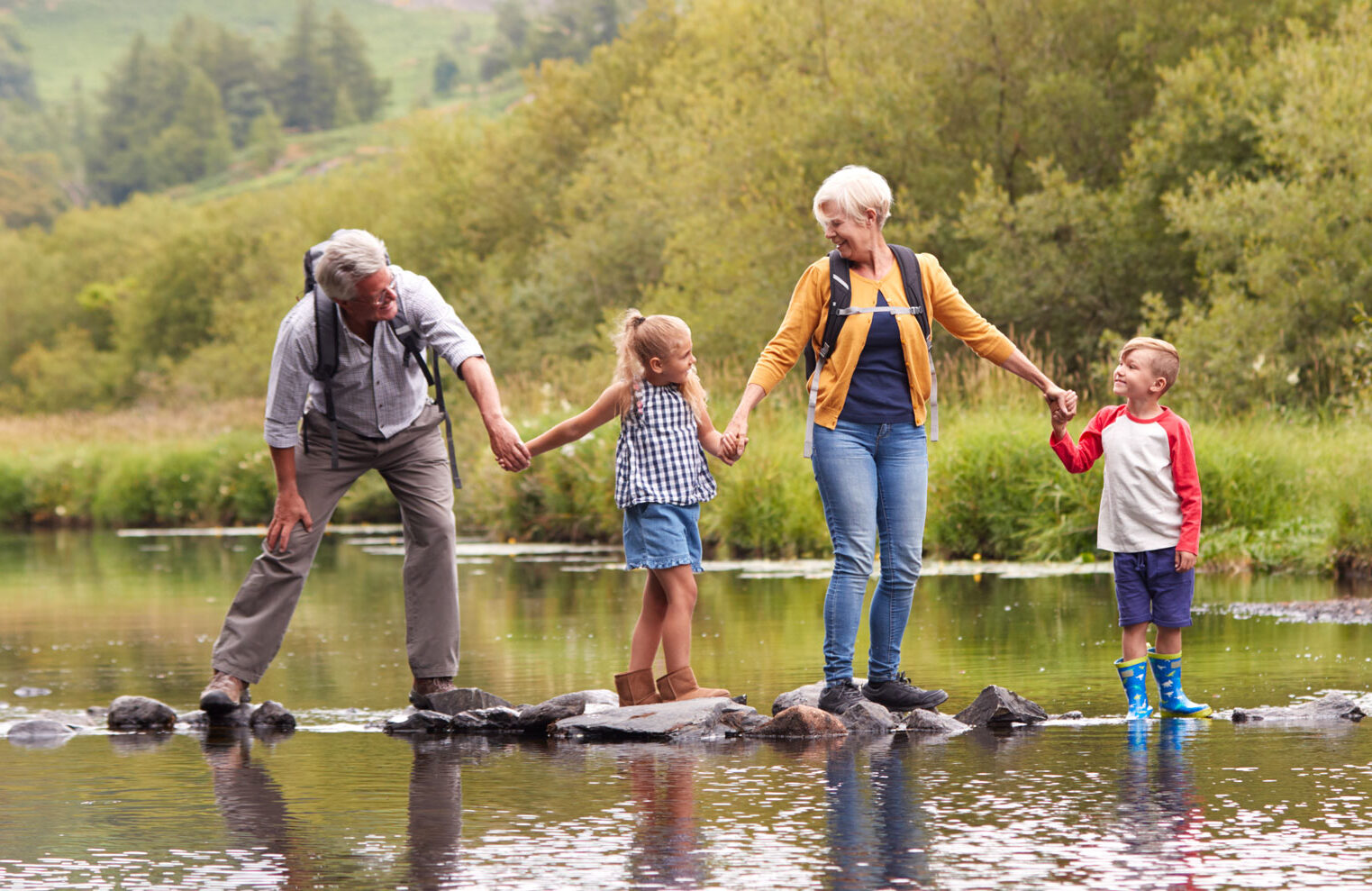banner seasonal summer grandparents hiking stream with grandchild