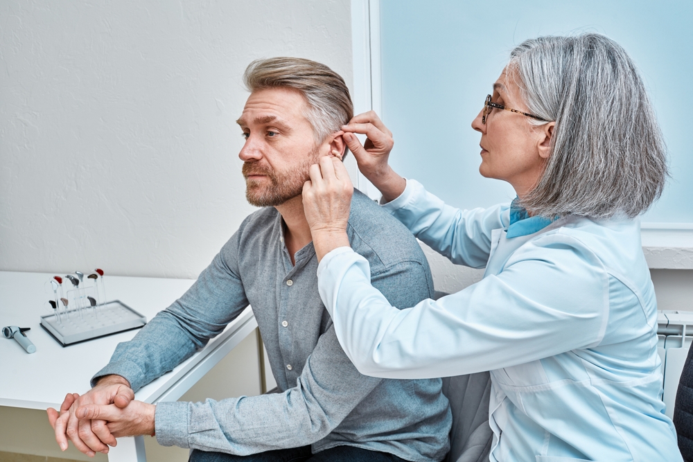 Experienced,Female,Doctor,Fitting,Intra the ear,Hearing,Aid,Into,Patient's,Ear