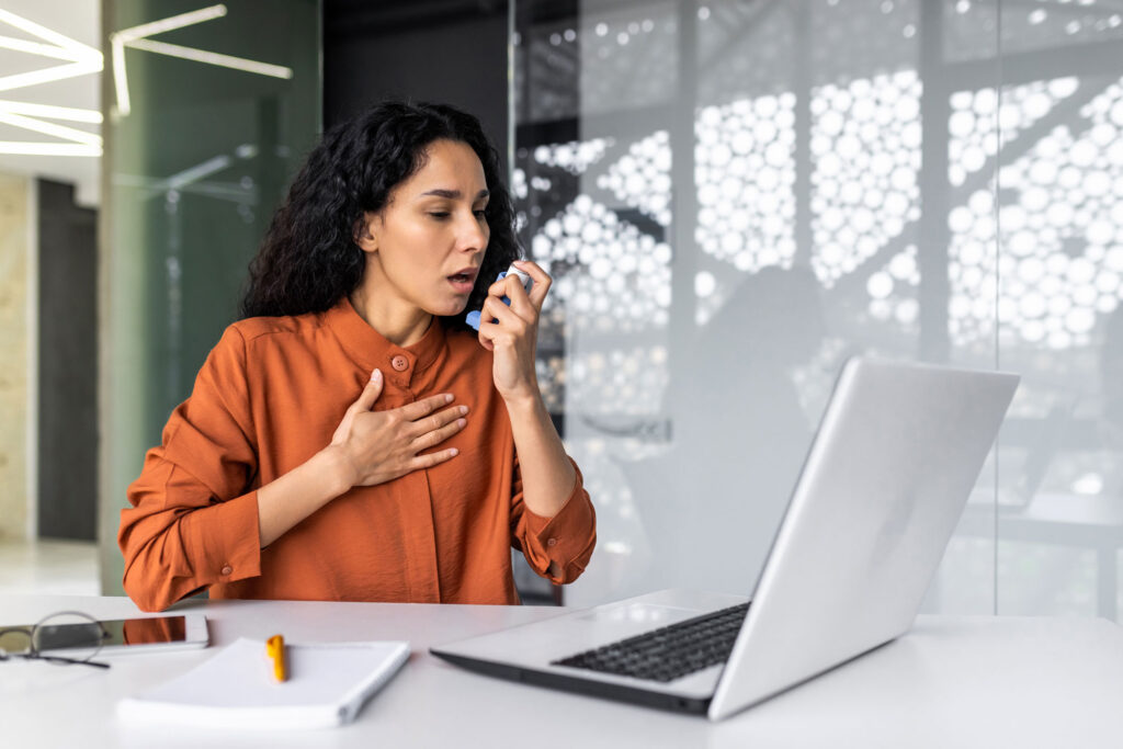 female worker using inhaler with medicine for breathing relief and asthma female worker using inhaler with medicine for breathing relief and asthma