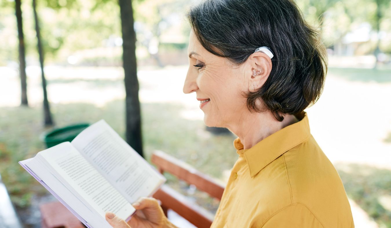 women outside reading with hearing aid