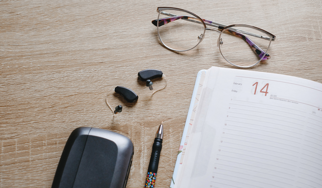 hearing aids devices only ric hearing aids with charging case on desk by calendar and glasses