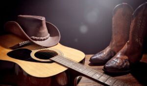 Country music festival live concert with acoustic guitar cowboy hat and boots background (1)