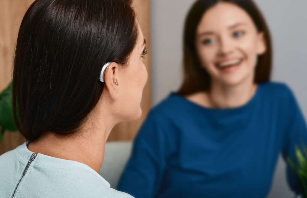 woman wearing hearing aid talking with woman