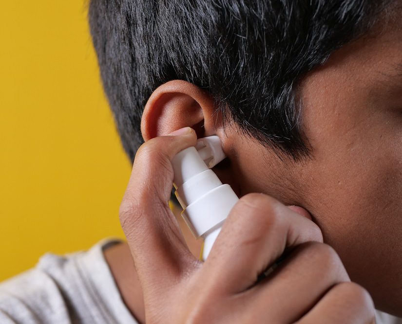man using spray to soften earwax