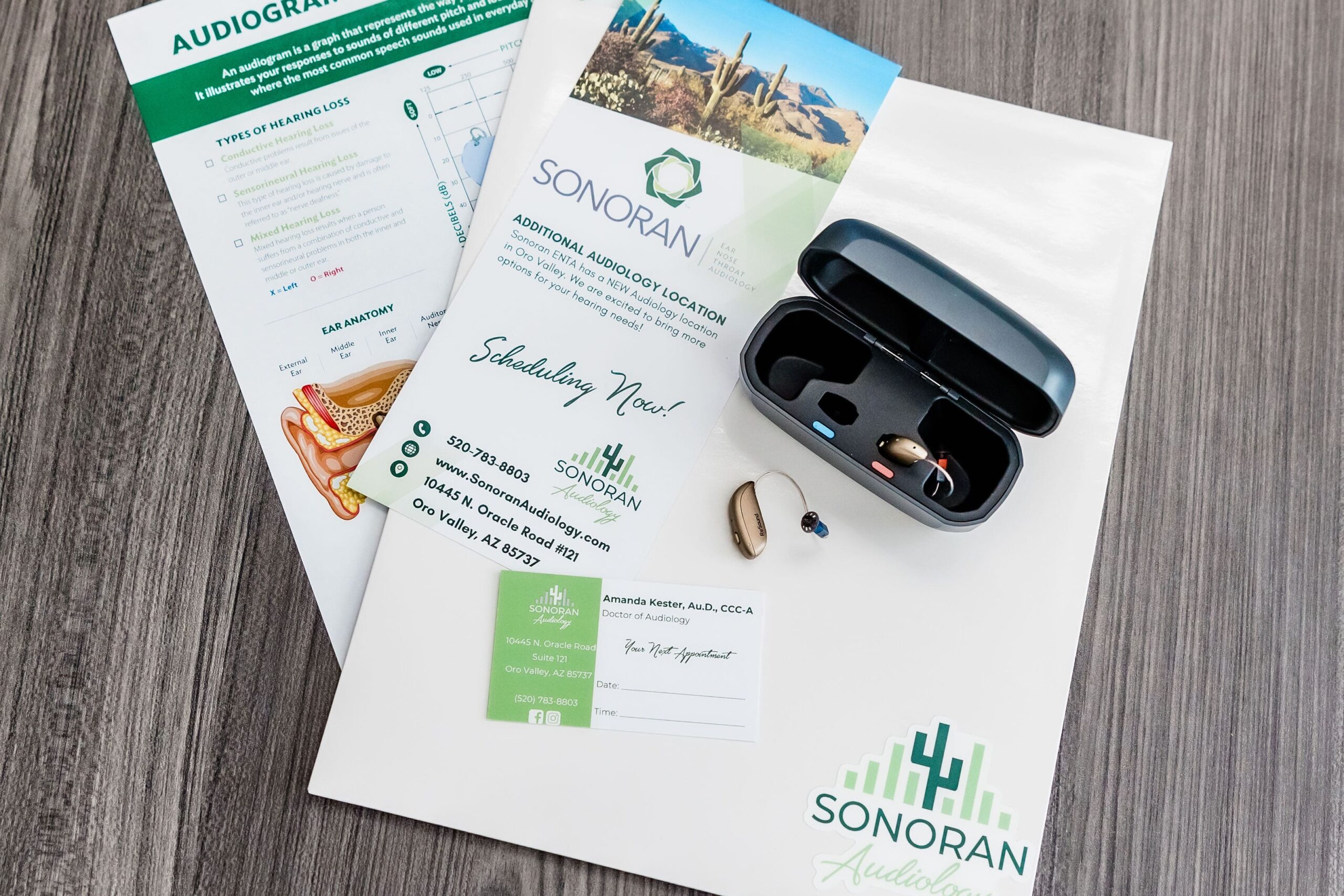 SonoranAudiology Marketing Material next to hearing aids, a rechargeable hearing aid case and additional hearing loss resources