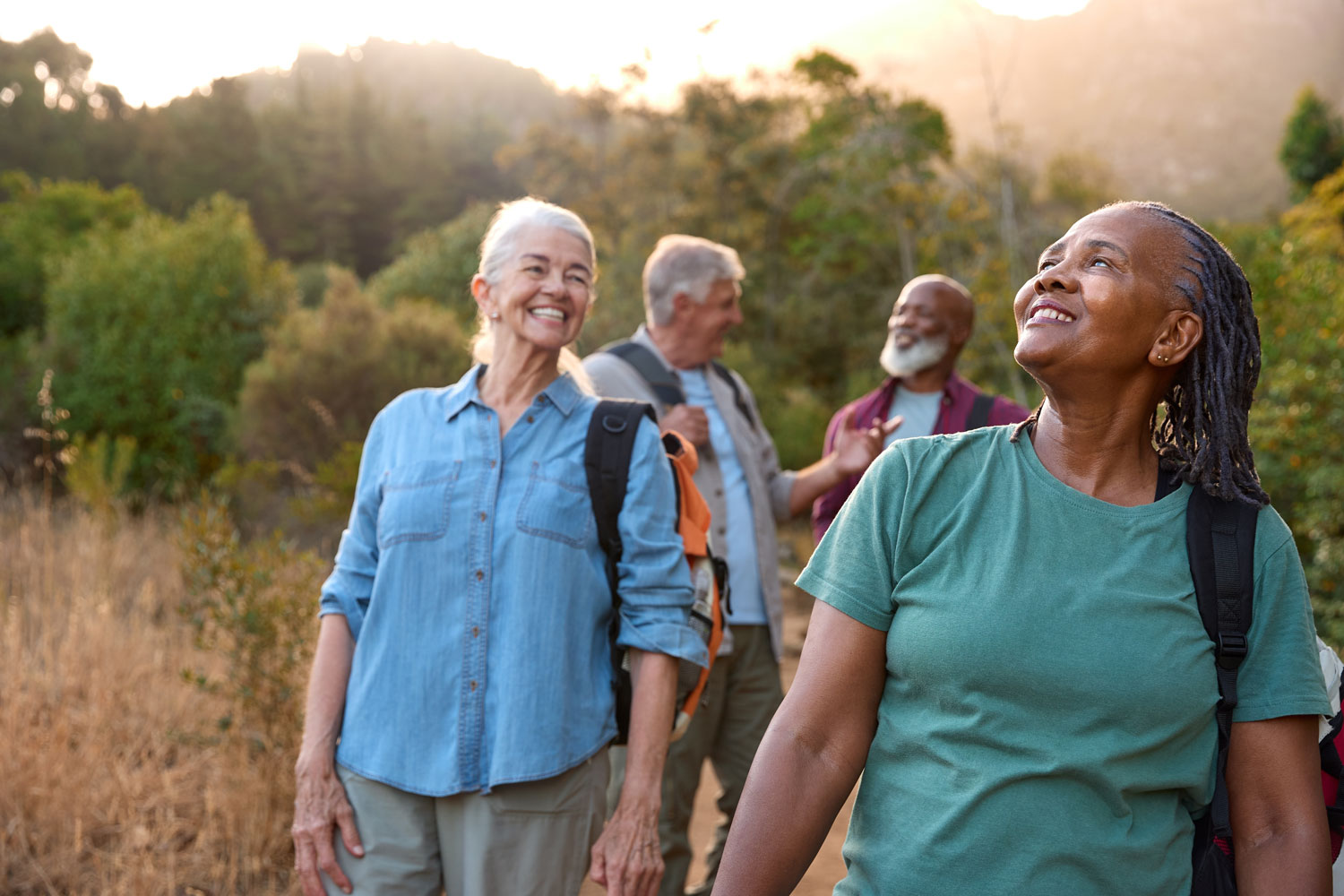 An older group of diverse friends hiking in the Arizona mountains, smiling and laughing with each other.